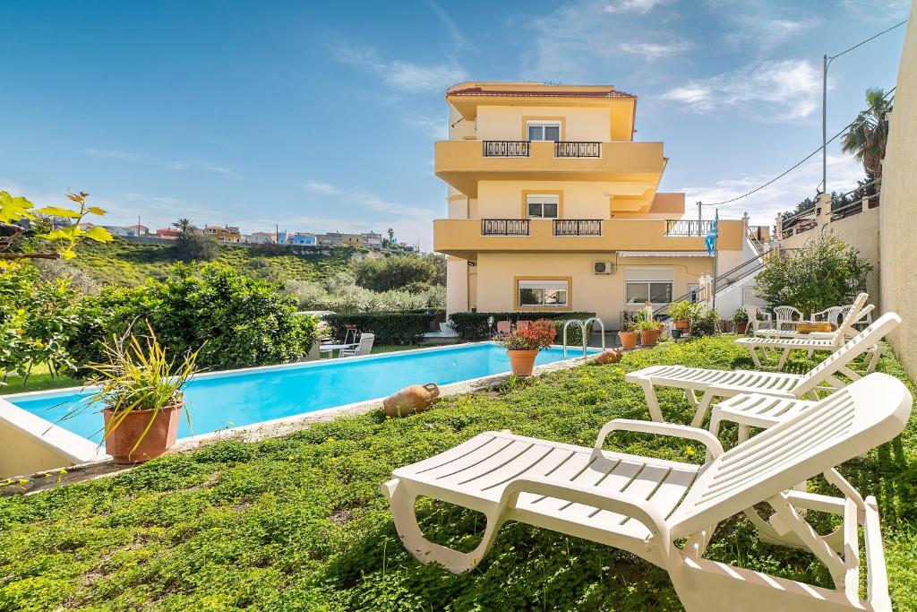 a house with a swimming pool and two white chairs at Rafaela's House in Koskinou