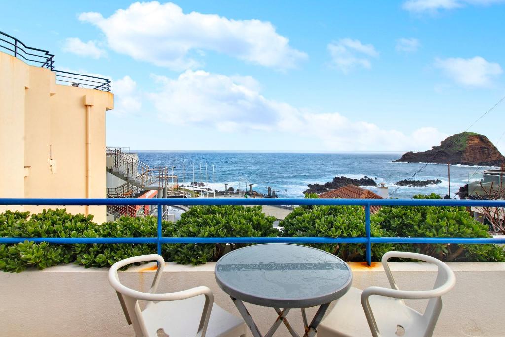 a balcony with a table and chairs and the ocean at Ninho Gaivota in Porto Moniz