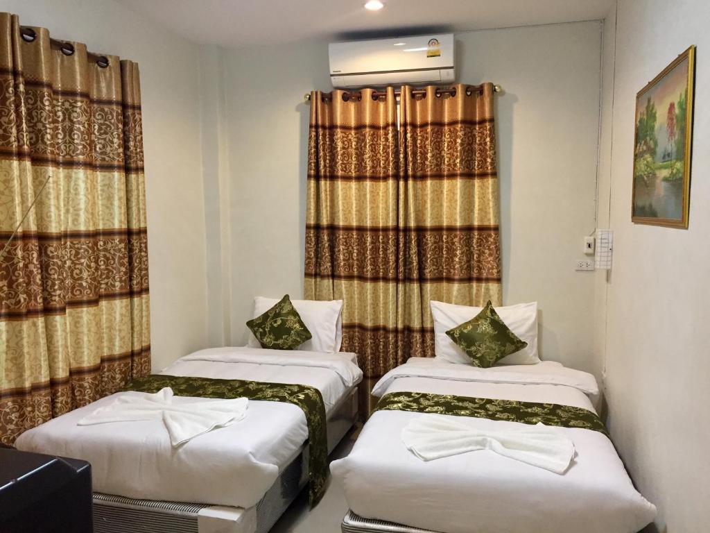 two beds in a small room with curtains at Apinsaya House in Ban Pa Sang (1)