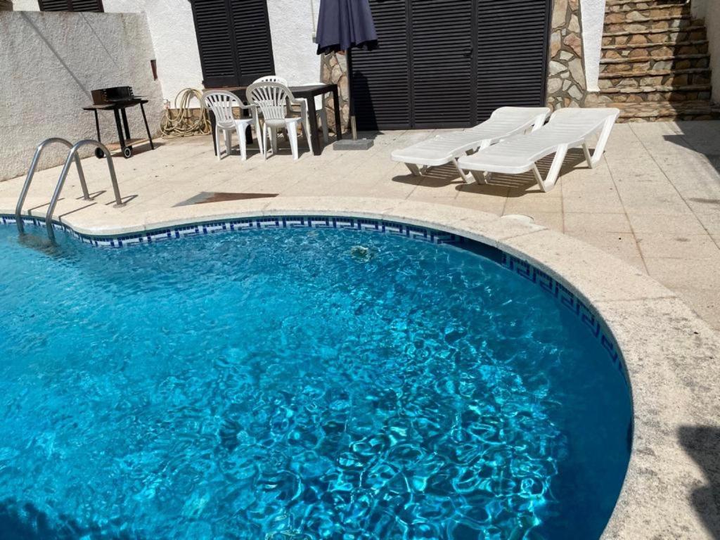 a large blue swimming pool with chairs and a table at Casa Saguer in L'Escala