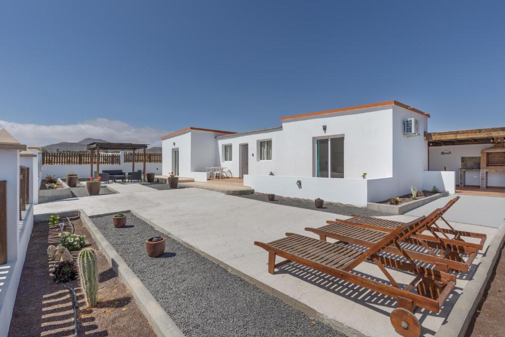 a courtyard of a white house with wooden benches at Rincón del olivar in Fuerteventura