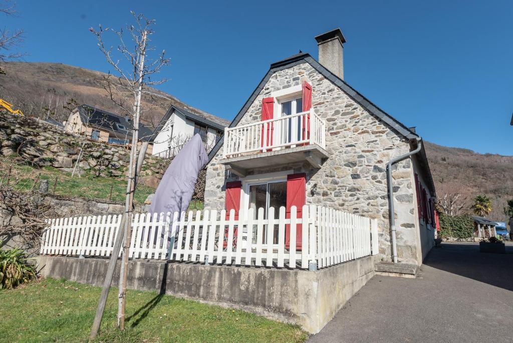 a small stone house with a white fence at Gite du Pibeste - 8 pers in Ouzous