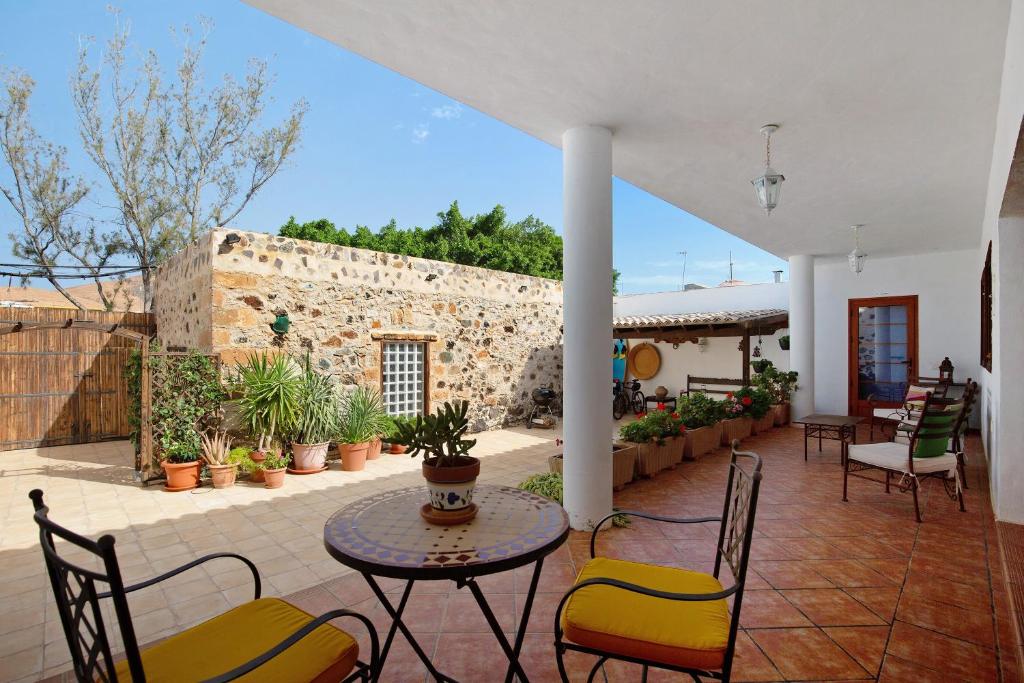 a patio with a table and chairs and a stone wall at Las Raíces in Pájara