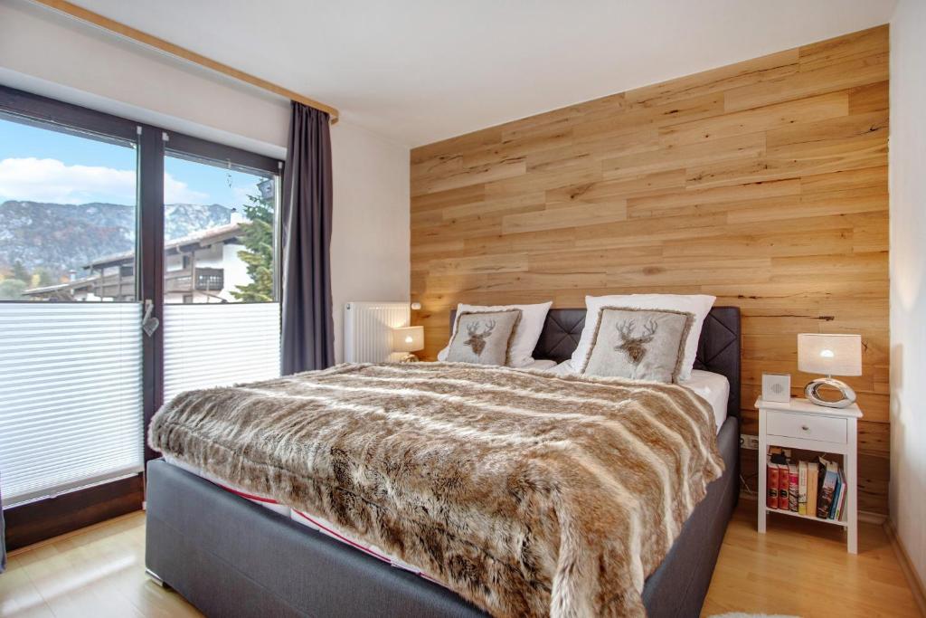 a bedroom with a large bed with a wooden wall at Ferienwohnung Marinas Alpenblick in Inzell