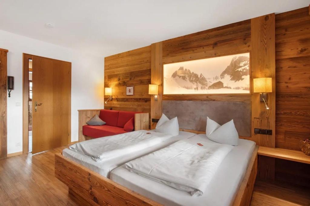 a bedroom with a large bed and a red couch at Gästehaus Panorama - Appartement 3 in Reit im Winkl