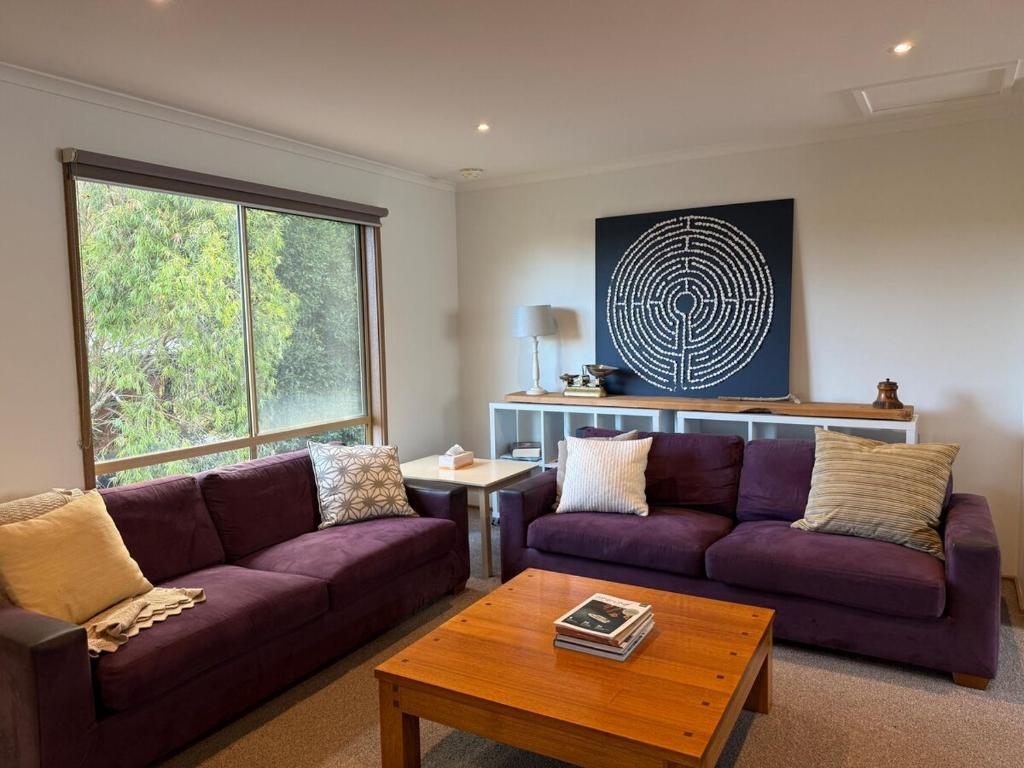 a living room with two purple couches and a table at Eunoia at Smiths in Smiths Beach