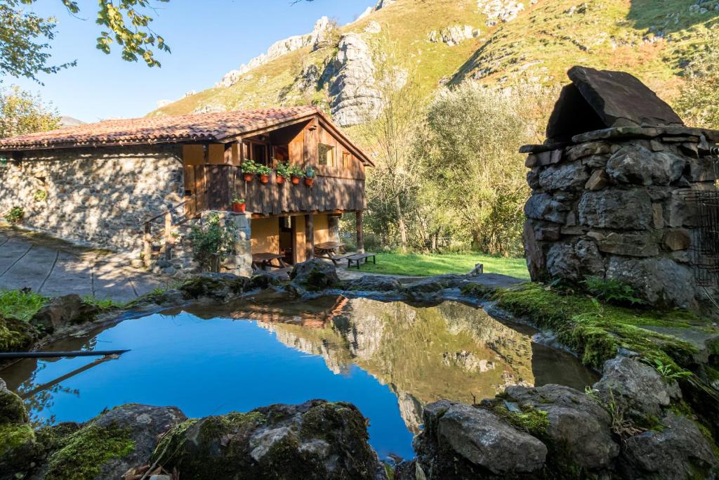 a house with a pond in front of a mountain at La Hirriria in San Roque de Ríomiera