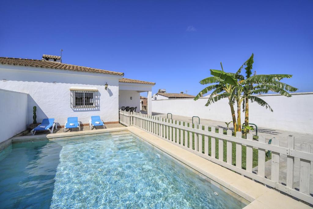 a swimming pool with two blue chairs and a fence at Villa Ibicenca in Vejer de la Frontera