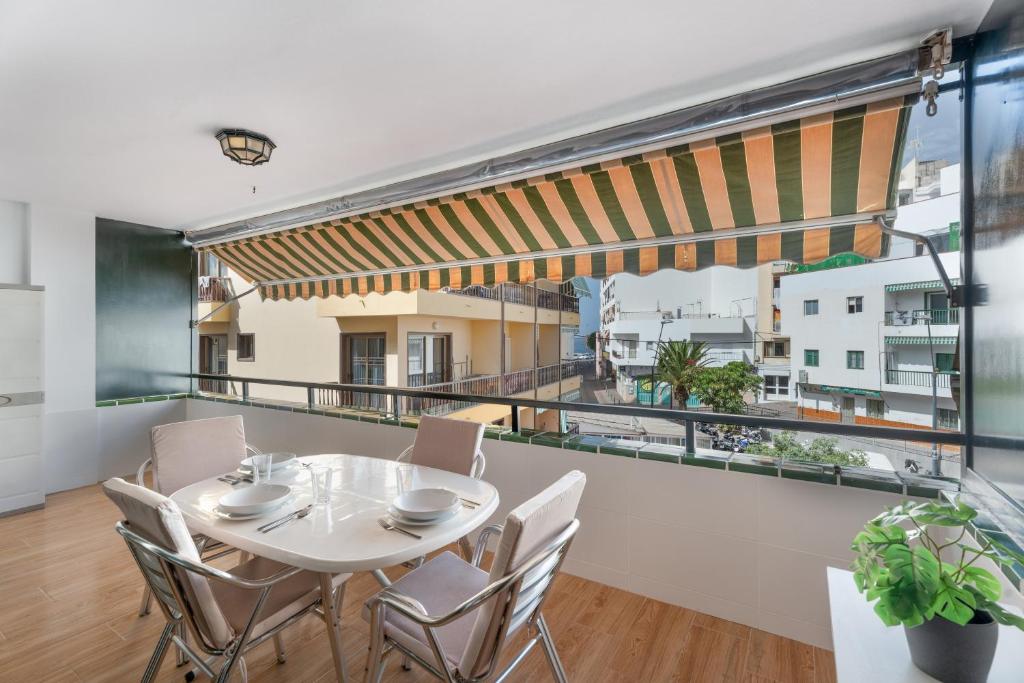 a dining room with a table and chairs and a balcony at Apto Tomasol in Los Cristianos