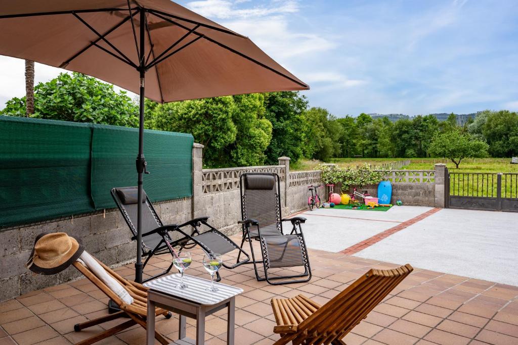 a patio with two chairs and an umbrella at Ca Carmina in Colunga