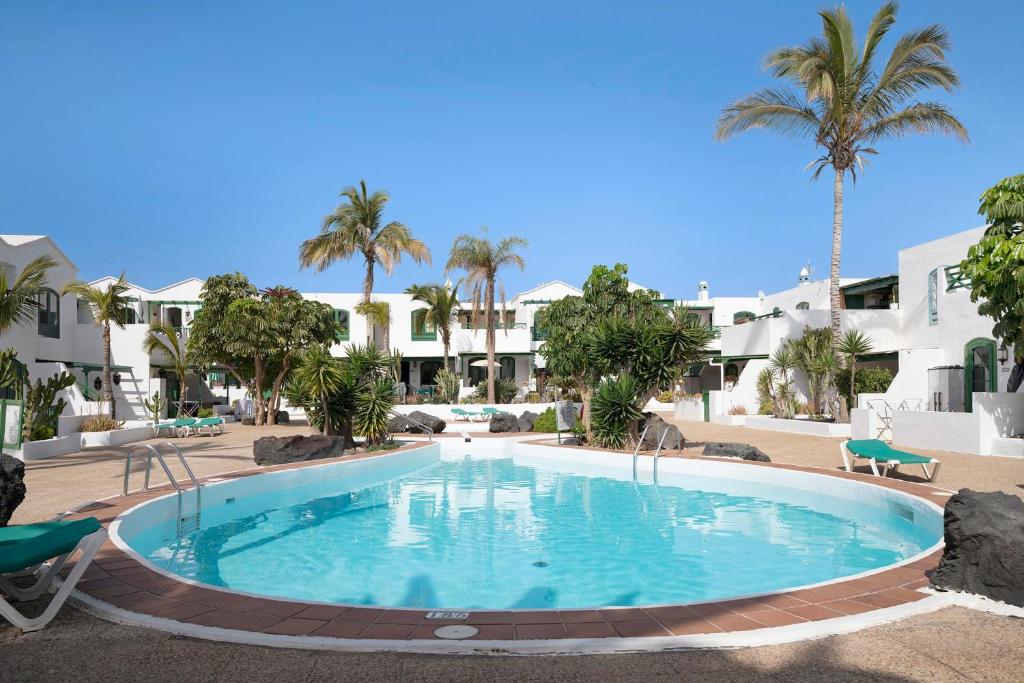 a large swimming pool in a resort with palm trees at Apartamento Rocas Negras in Puerto del Carmen