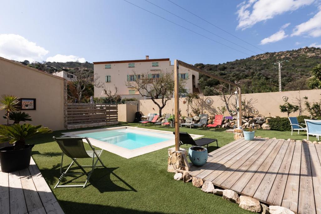 a backyard with a swimming pool and a wooden deck at A Casa Assulanata Cinto in Santa-Reparata-di-Balagna