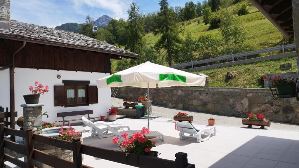 a patio with an umbrella and chairs and a table at Maison Sylvie Pila in Gressan