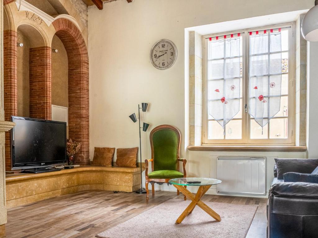 a living room with a tv and a green chair at Le Cocon in Villalier