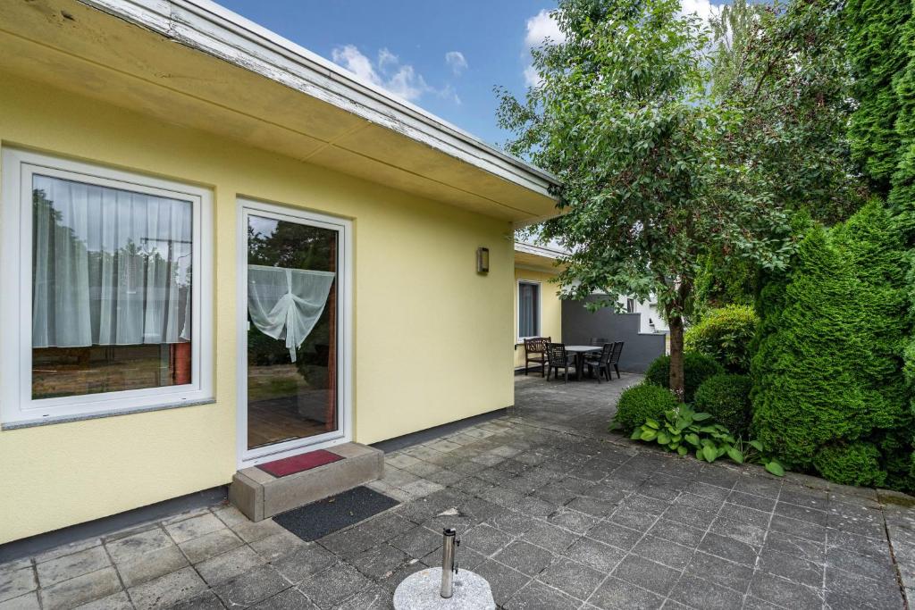 a yellow house with a patio and a tree at Bungalow 71 in Zeulenroda