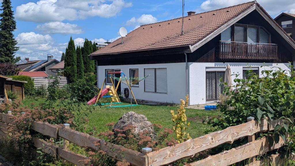 a small white house with a playground in the yard at Ferienwohnung Wittle in Weiler-Simmerberg