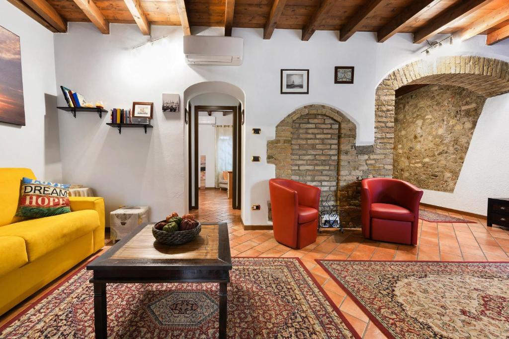 a living room with a yellow couch and red chairs at Casa Laura in Salò