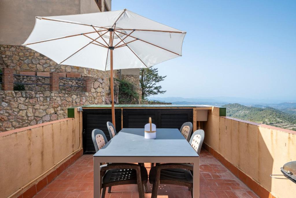 ein Tisch und Stühle mit einem Sonnenschirm auf einem Balkon in der Unterkunft Cal Cosials in La Morera de Montsant