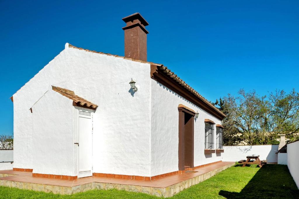 a white church with a steeple and a grass yard at Las Calas de Roche in Roche