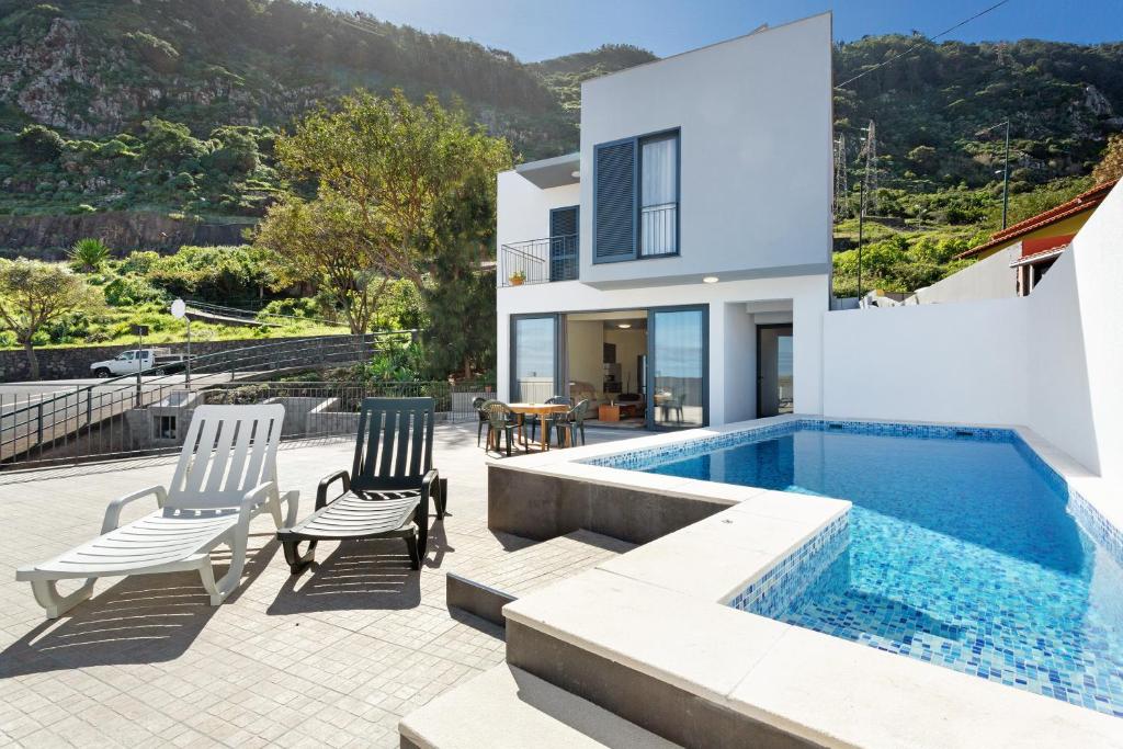 a house with a swimming pool and two chairs at Casa da Pontinha in Machico