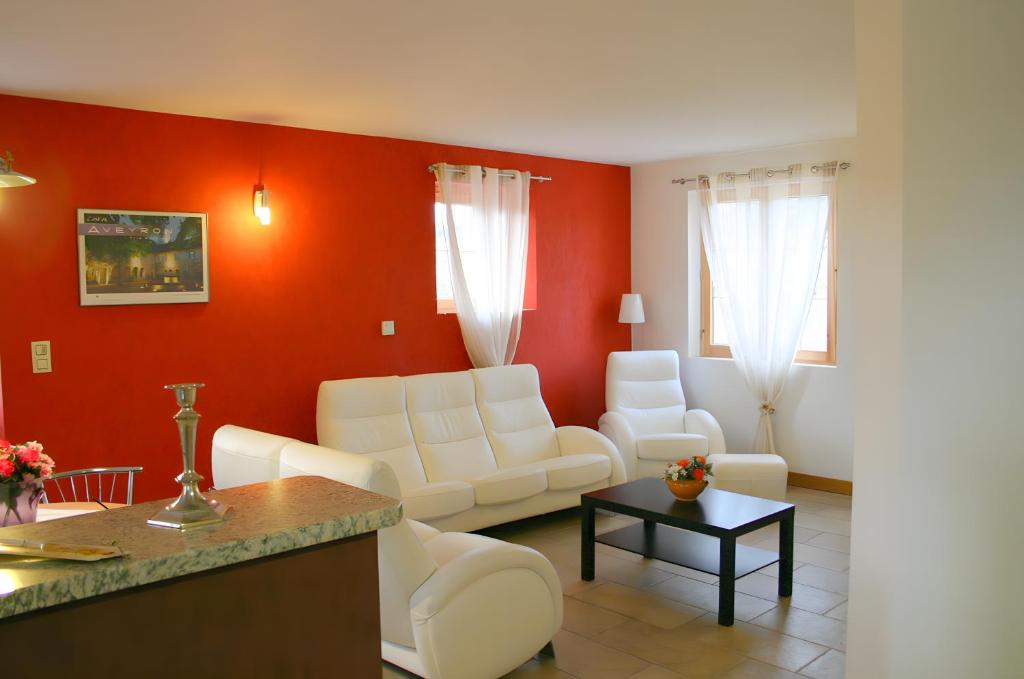 a living room with white furniture and a red wall at Le Genévrier - Gites Rocheflamme in La Malène