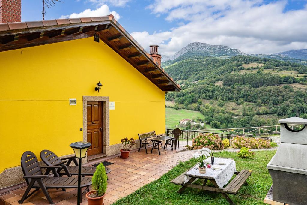 ein gelbes Haus mit einem Tisch und Stühlen auf einer Terrasse in der Unterkunft Socastillo B in Bárzana