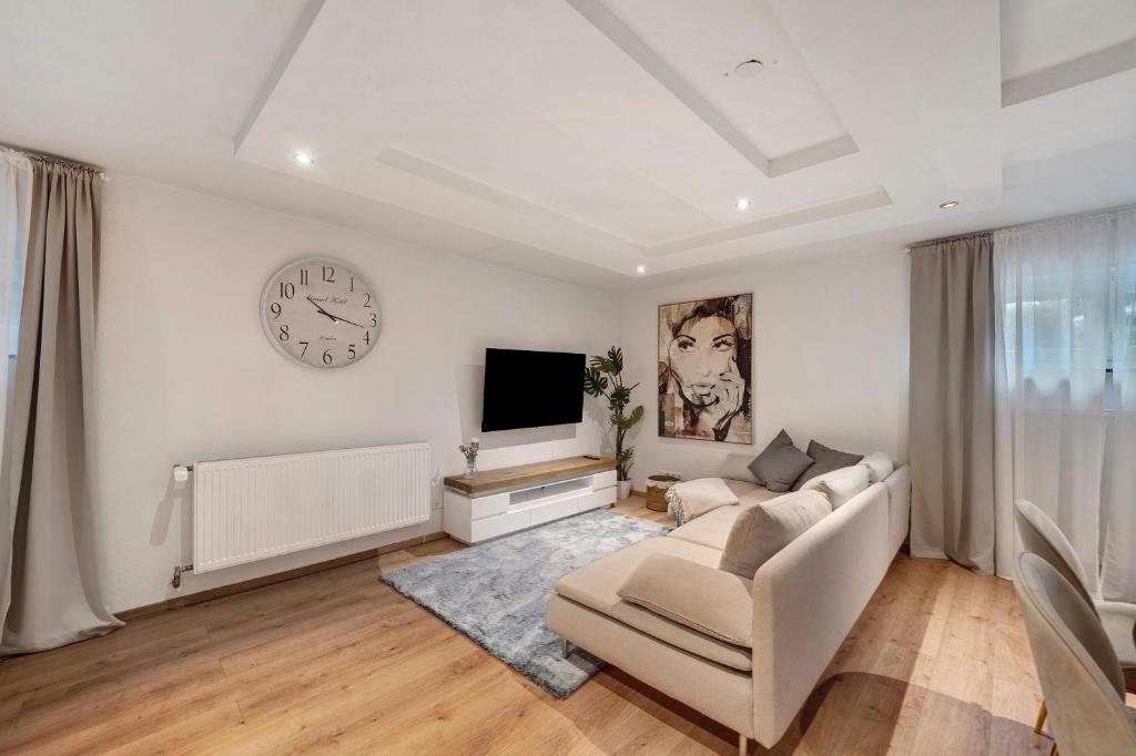 a living room with a couch and a clock on the wall at Modern und gemütlich- in Teningen in Teningen