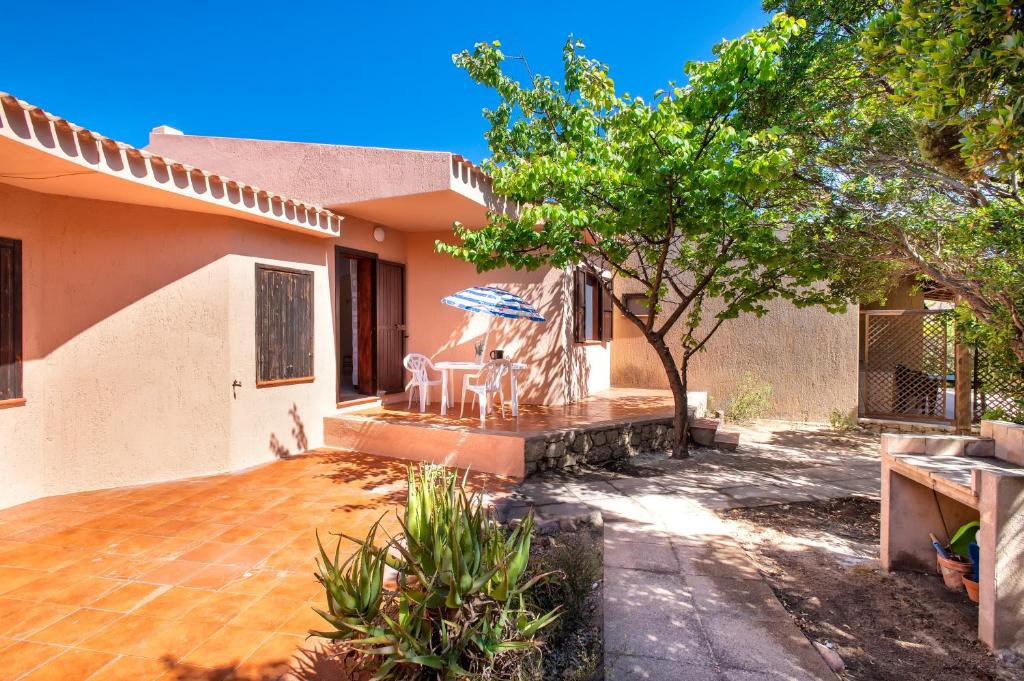 a house with a patio with chairs and an umbrella at Casetta paradiso in Costa Paradiso