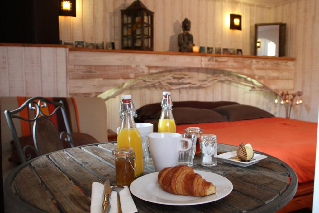 a table with a plate of bread and bottles of orange juice at La chambre L'ile de Tom in Lège-Cap-Ferret