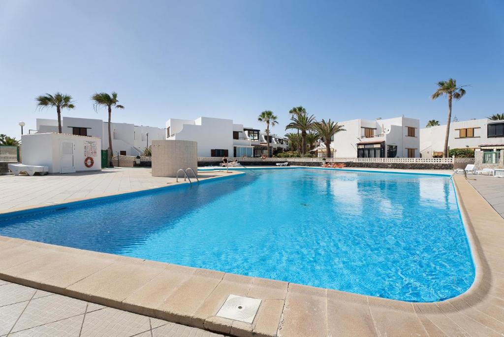 a large blue swimming pool with palm trees and buildings at Casa Relax Marine in Costa Del Silencio