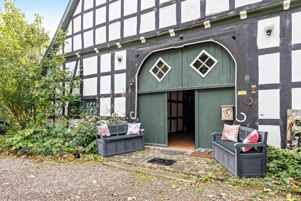 a building with a green door and two chairs at Wie Bei Muddi in Lübbecke