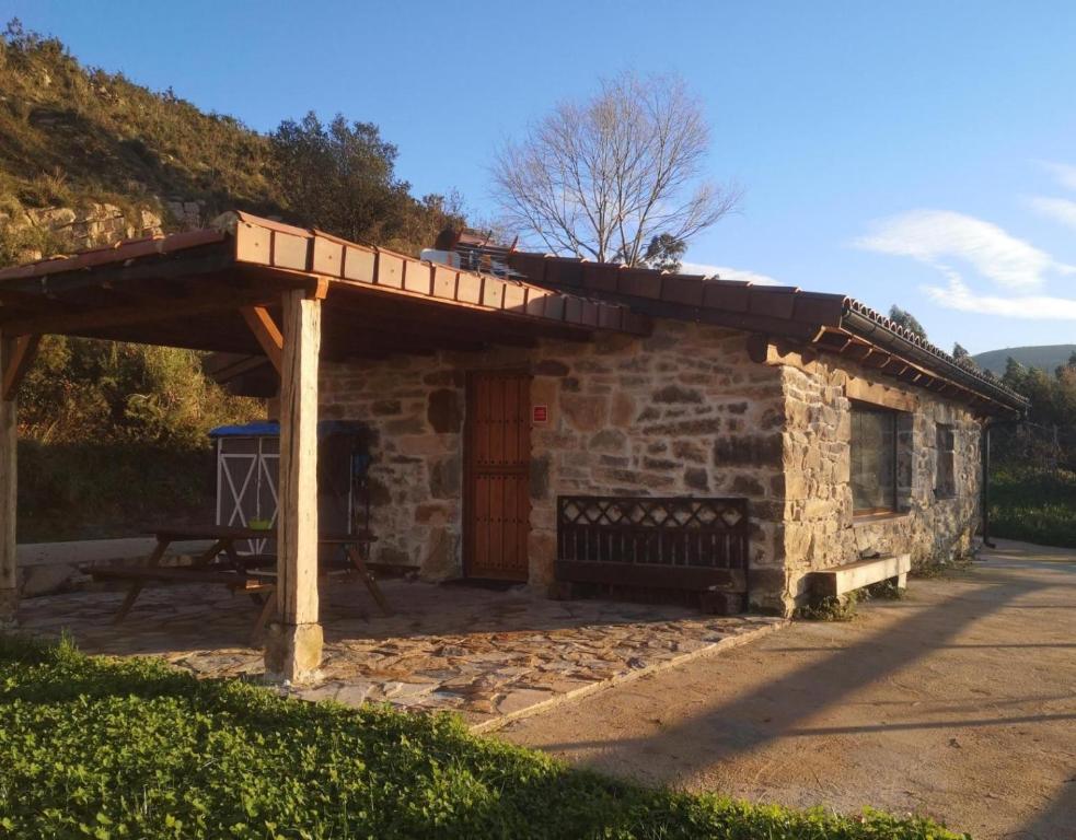 a stone building with a wooden pergola at Casa Rural El Picón in Entrambasaguas