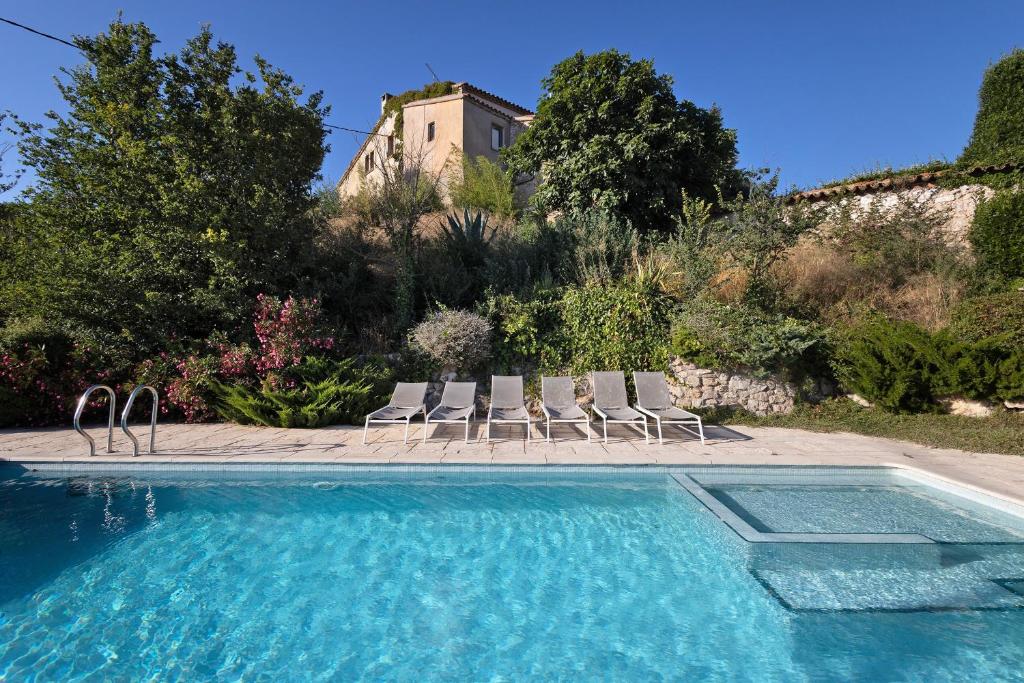 a swimming pool with chairs and a house in the background at Casa Espigol in El Bruc