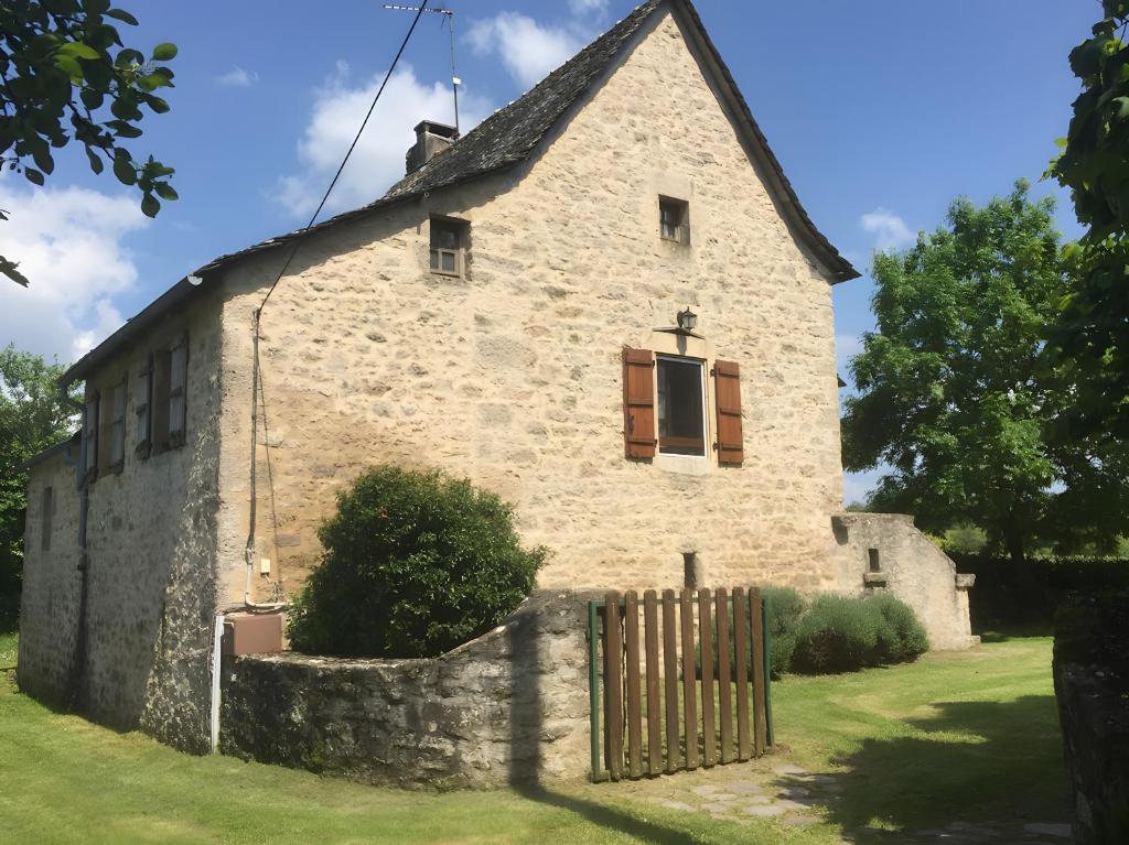 an old stone building with a fence in the grass at Gîte Du Cayrou in Bournazel