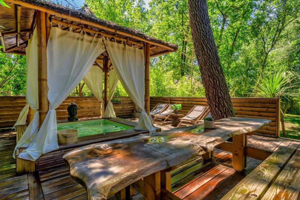 a hot tub on a deck with a gazebo at Chalet Bangli in Lacanau