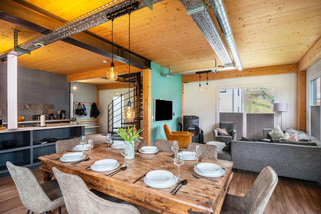 a dining room and living room with a wooden table and chairs at Moselbude Cube mit Sauna in Traben-Trarbach