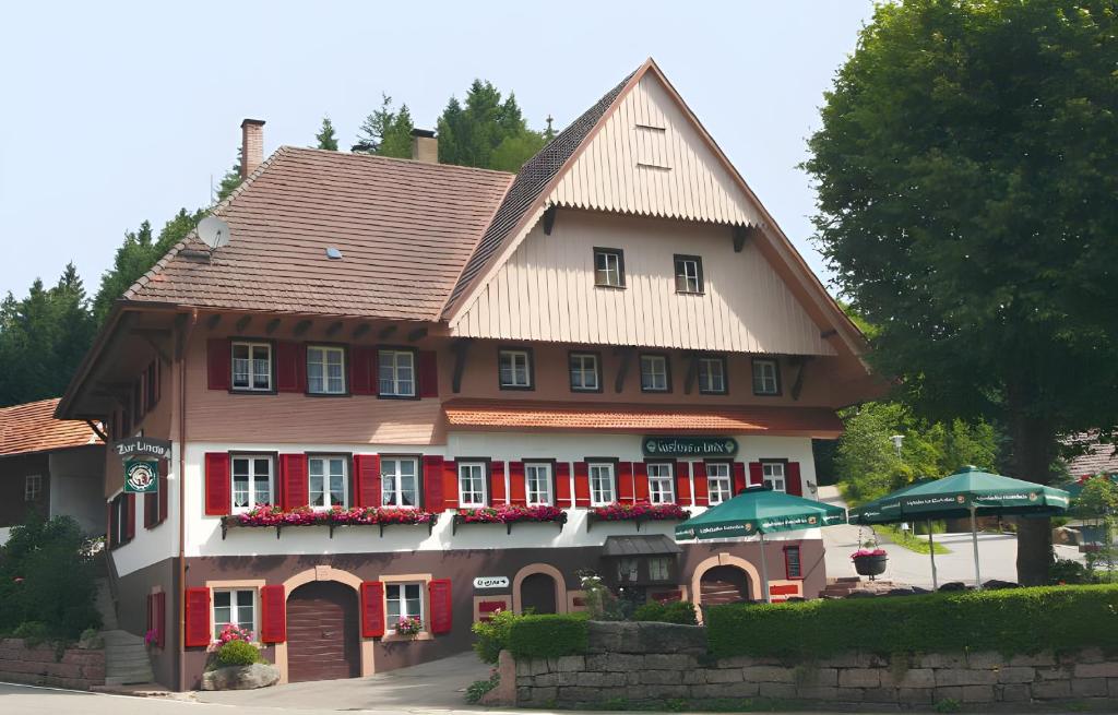 a large building with red doors and a roof at Gasthaus Zur Linde Ferienwohnungen in Oberharmersbach