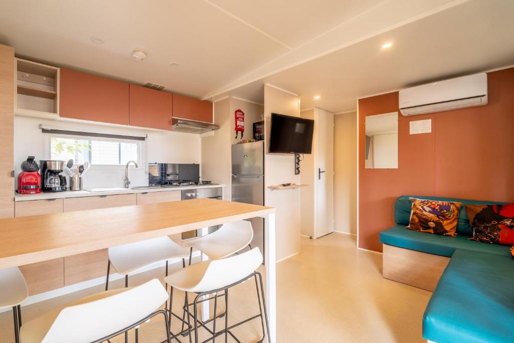 a kitchen and living room with a blue couch at Mobilhome au Camping La Yole in Vendres