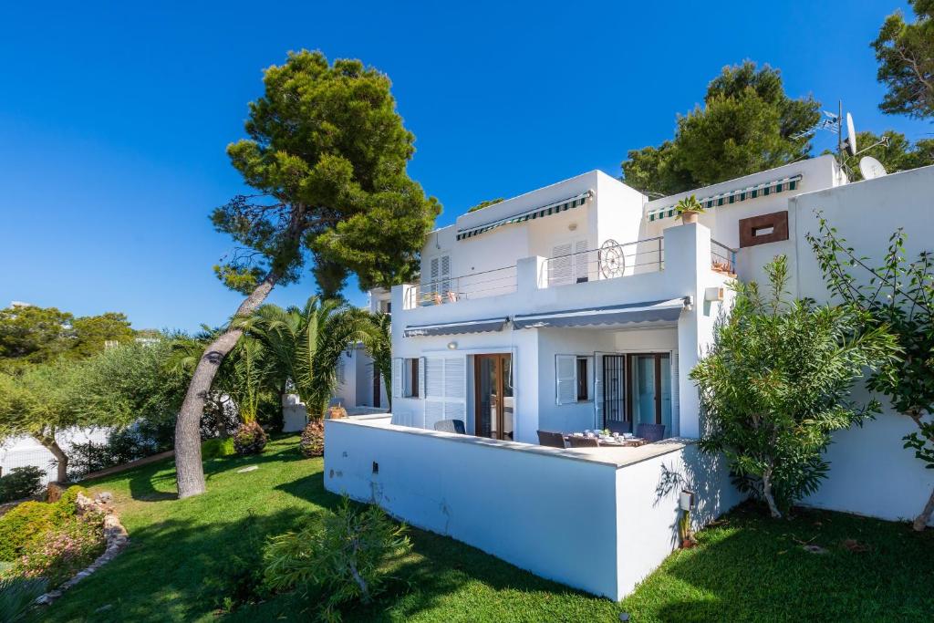 a white house with a green yard at Beach Apartment 11 in Cala d´Or