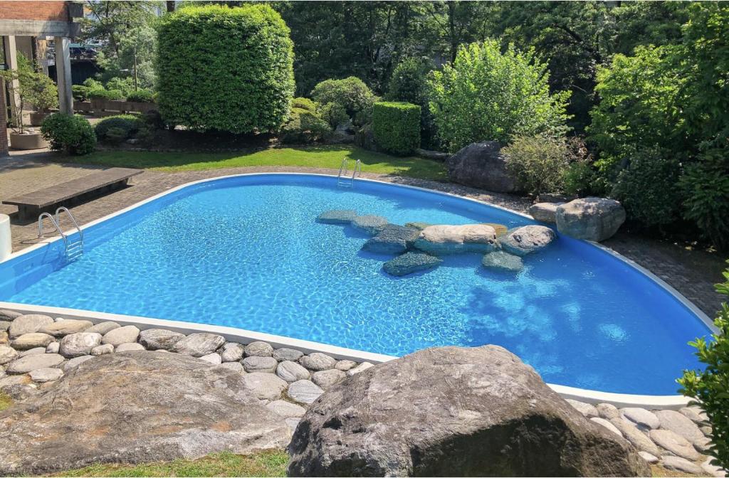 a large swimming pool with rocks in a yard at Appartement im Park in Minusio