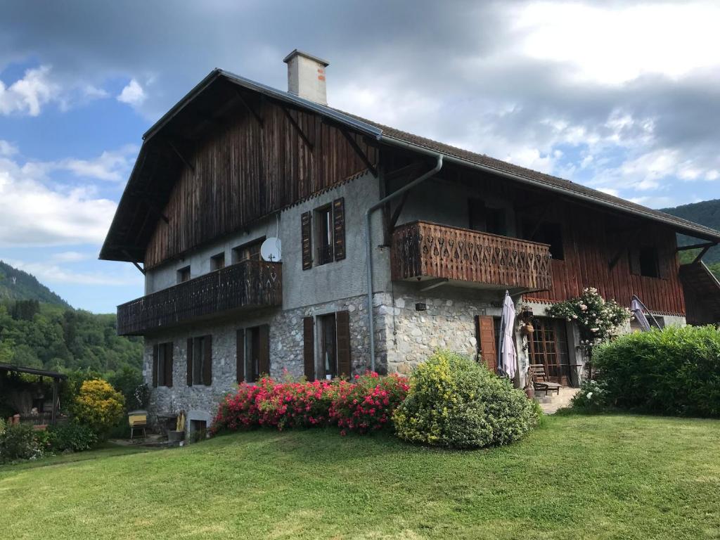 a house with a wooden roof and a grass yard at Séjour dans ferme de 1876 in Marignier