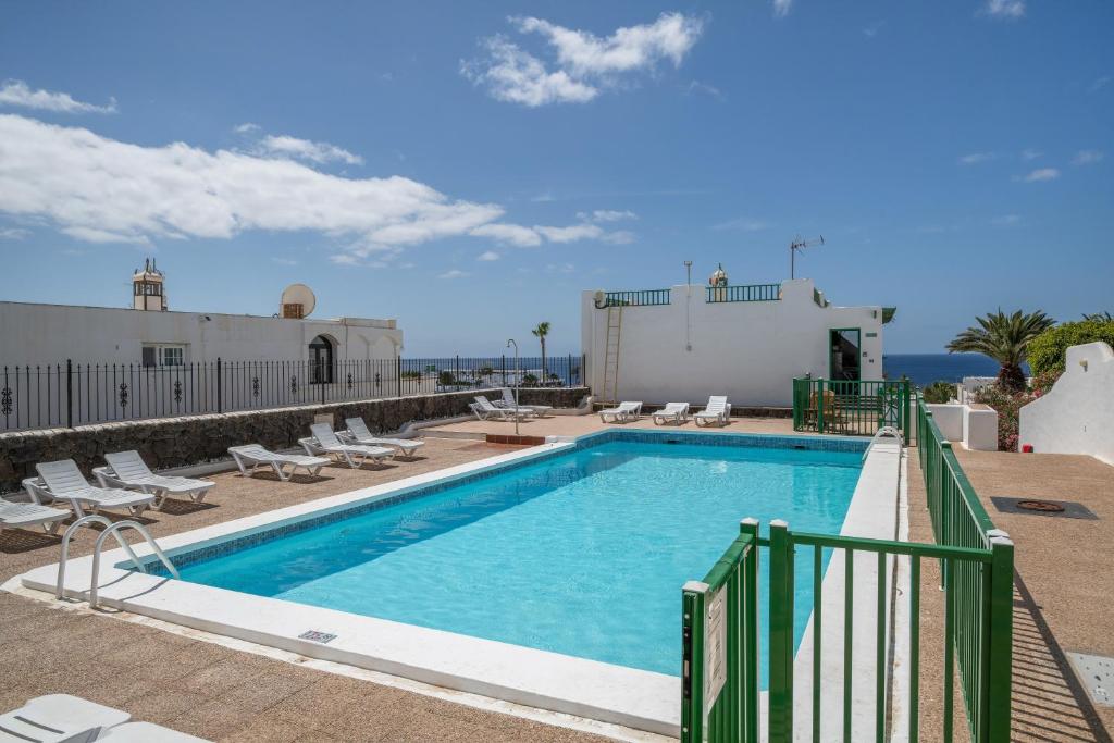 a swimming pool with chaises and chairs next to a building at Apartamento Princesa Teguise in Tías