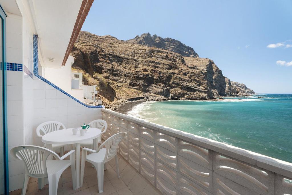 a balcony with a table and chairs and the ocean at Apartamentos Playa Azul - 7 in Vallehermoso
