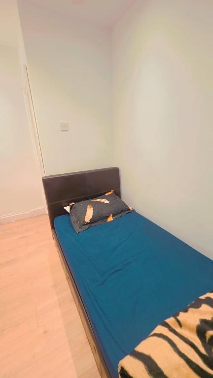 a small bed in a room with a blue bedsheet at Ascot Room in Slough