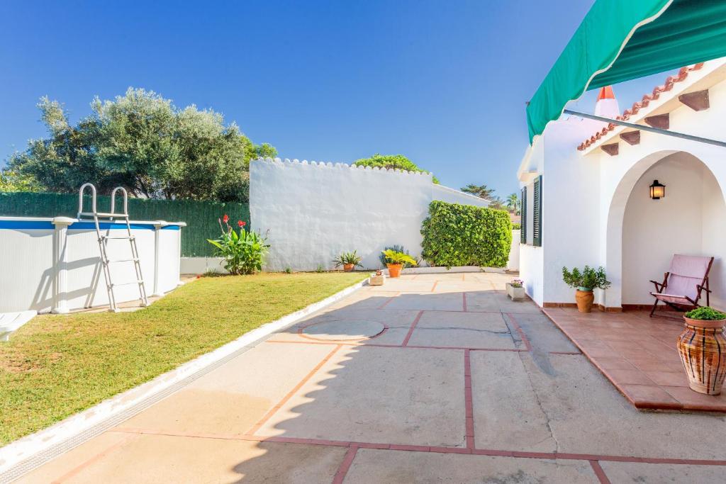 a garden with a white wall and a patio at Sa Sivina in Cala en Bosc