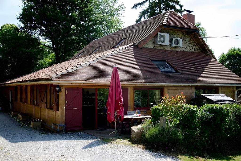 a house with a table and a red umbrella at Chambre D'hôtes Du Mas in Saint-Vitte-sur-Briance