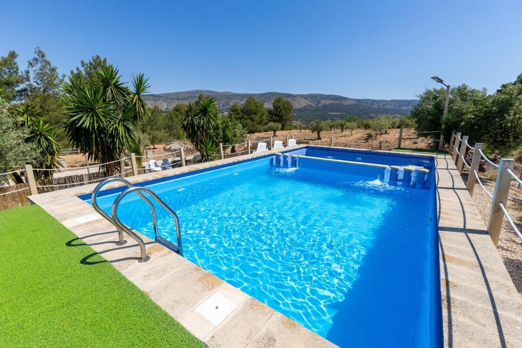a blue swimming pool with a green lawn at Rustic Escape by Fidalsa in Ibi