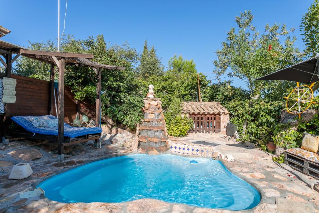 a swimming pool in a yard with a stone fountain at La Cuina De Paqui in Caserío Calandari