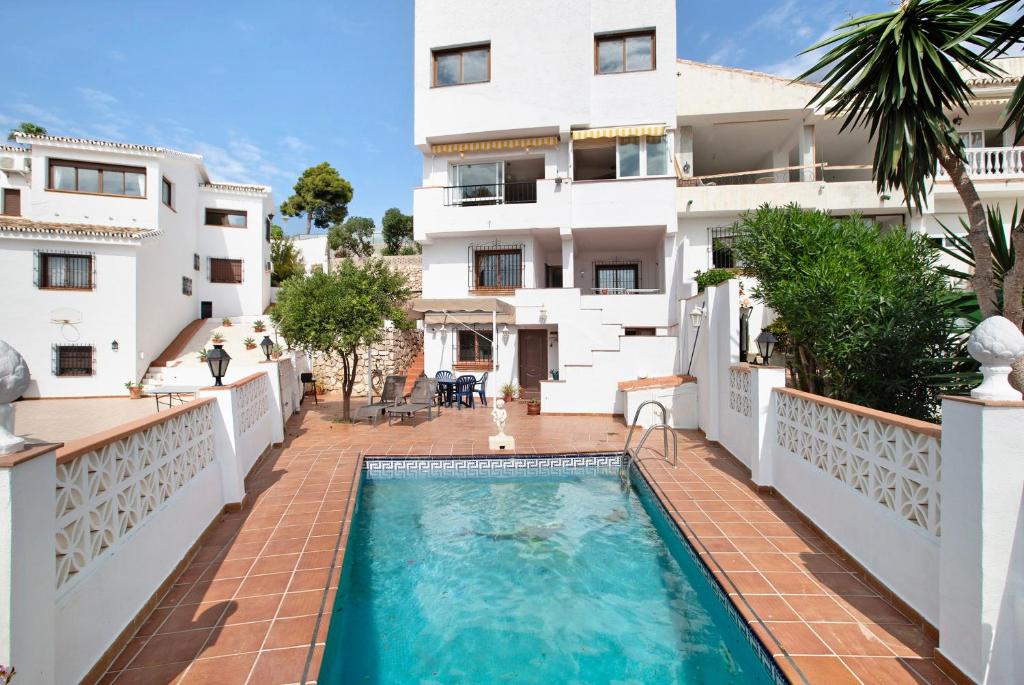 an apartment with a swimming pool in front of a building at Casa Torremuelle in Benalmádena