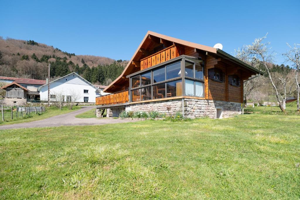 a log home with a large deck on a grass field at Chalet de Monique in Le Val-dʼAjol